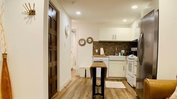 Uma sala de estar moderna com piso de madeira, um sofá de couro marrom e uma mesa de centro de vidro com controles remotos e um cartão.