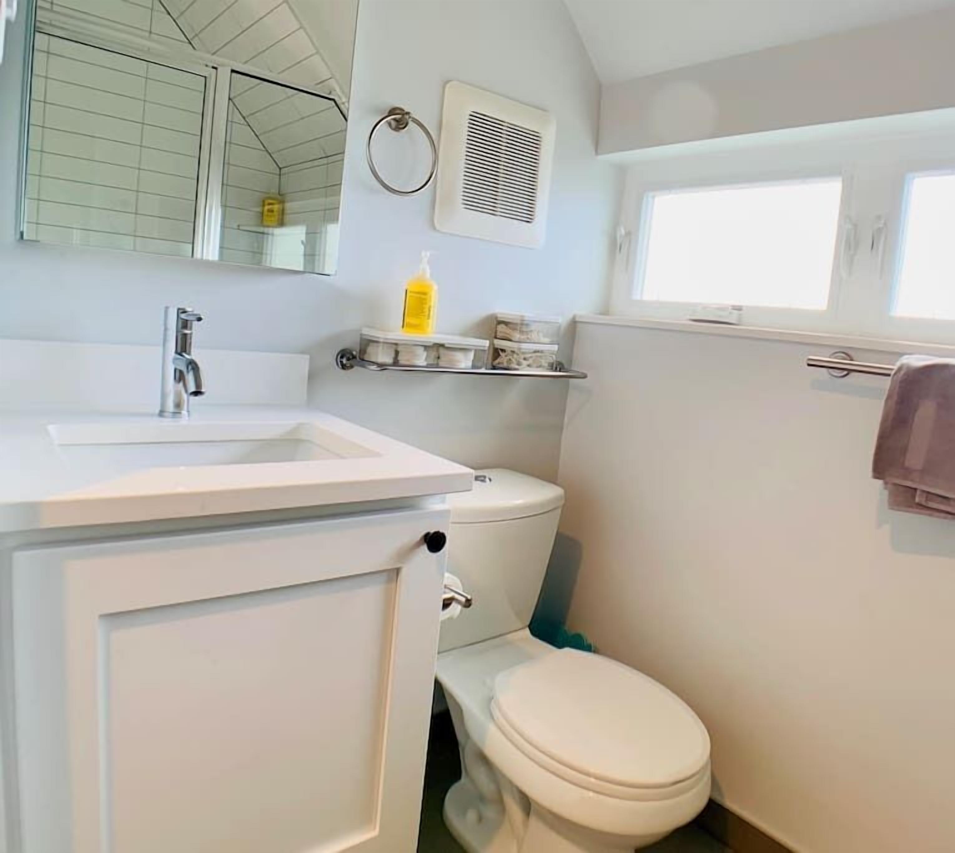 Un baño pequeño con lavamanos, inodoro y una ventana.