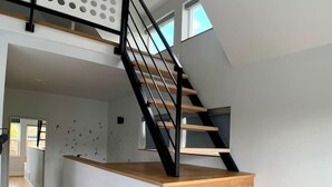 A modern staircase with wooden steps and black railings, leading to an upper floor. - Birdhouse on Green Lake (Seattle)