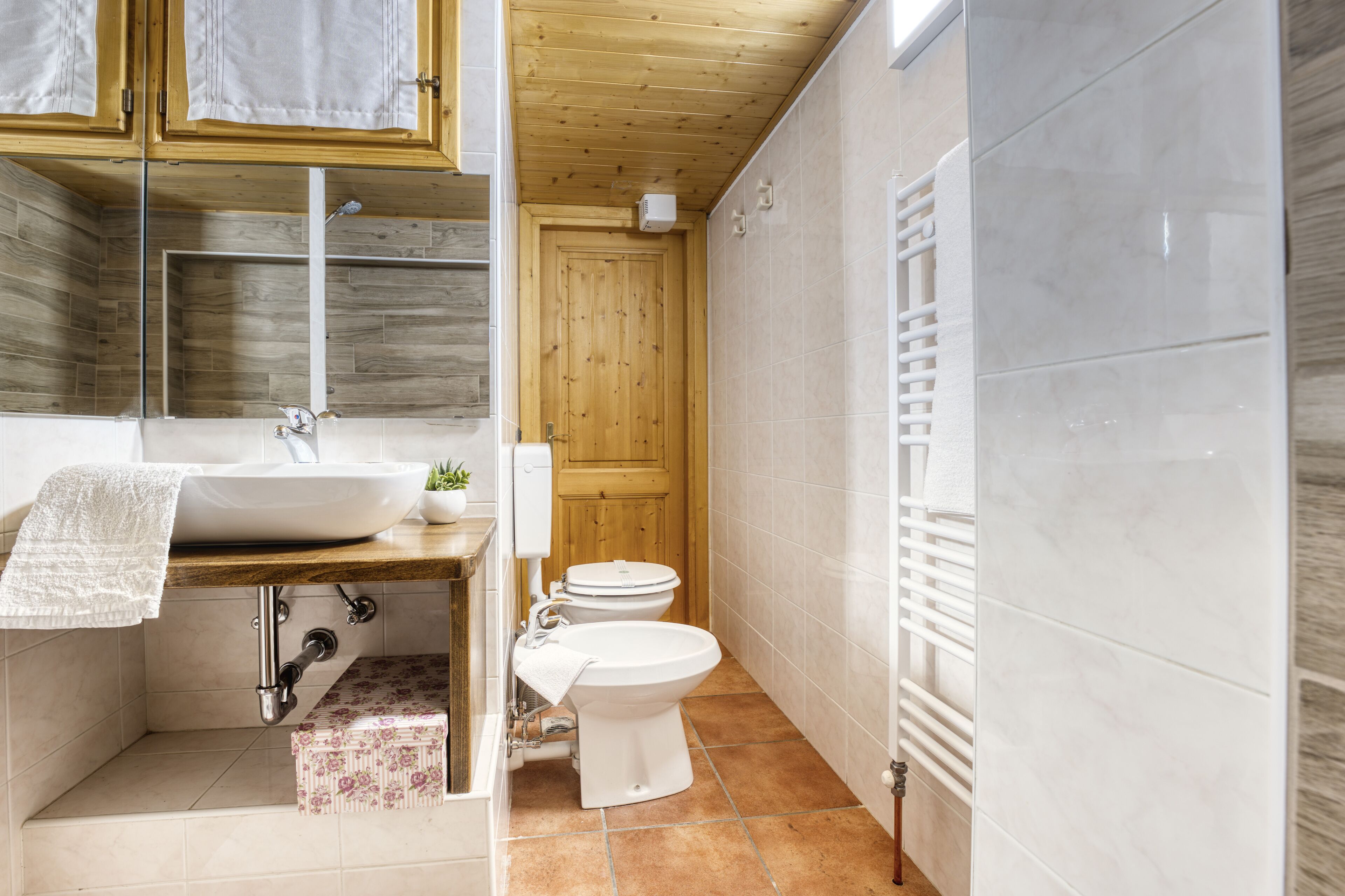 A bathroom with a wooden vanity, a sink, a toilet, and a towel rack.