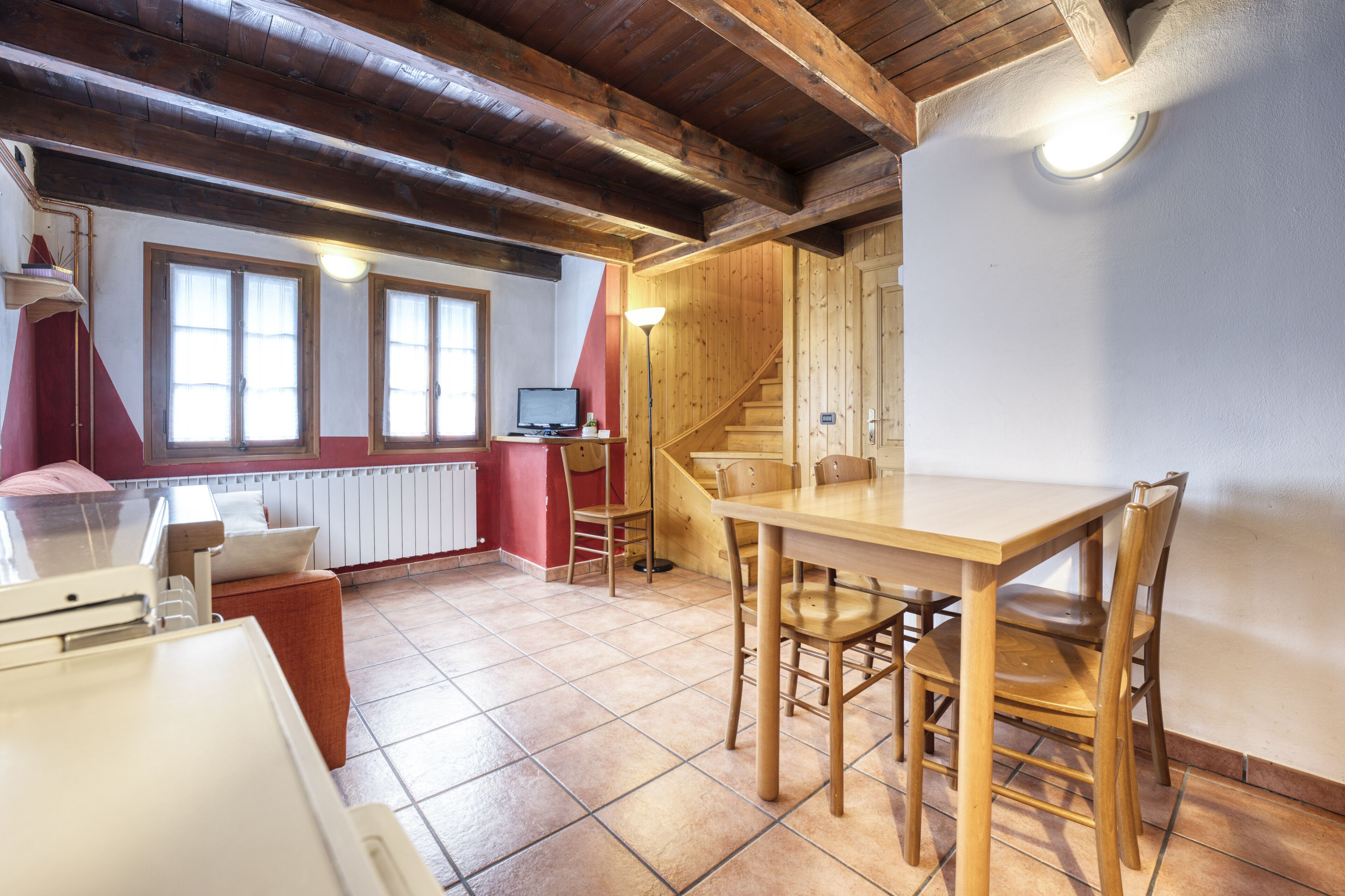 Una habitación acogedora con una mesa y sillas de madera, una cama y una escalera.