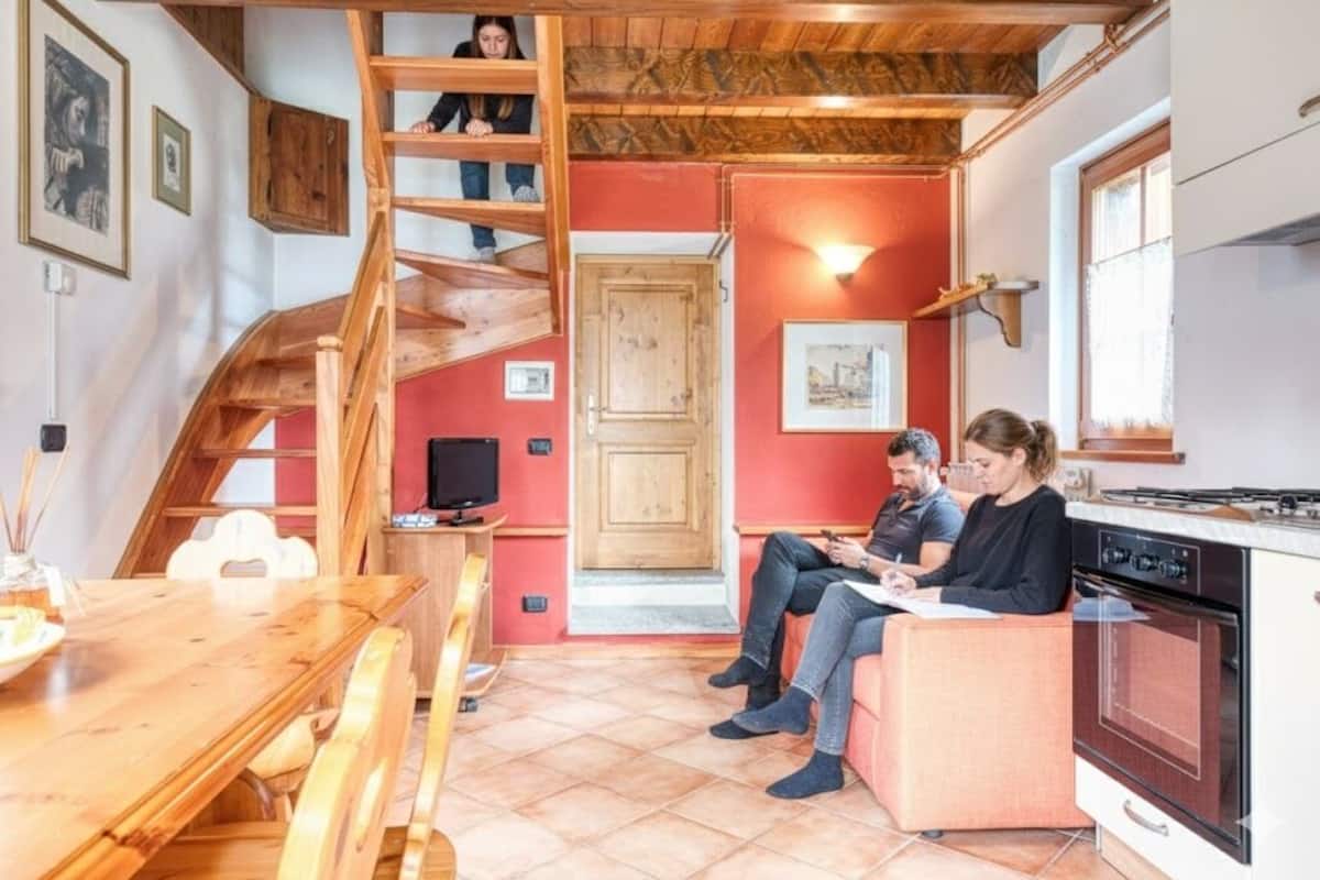 A cozy interior with a wooden staircase, a dining area, and a kitchen.