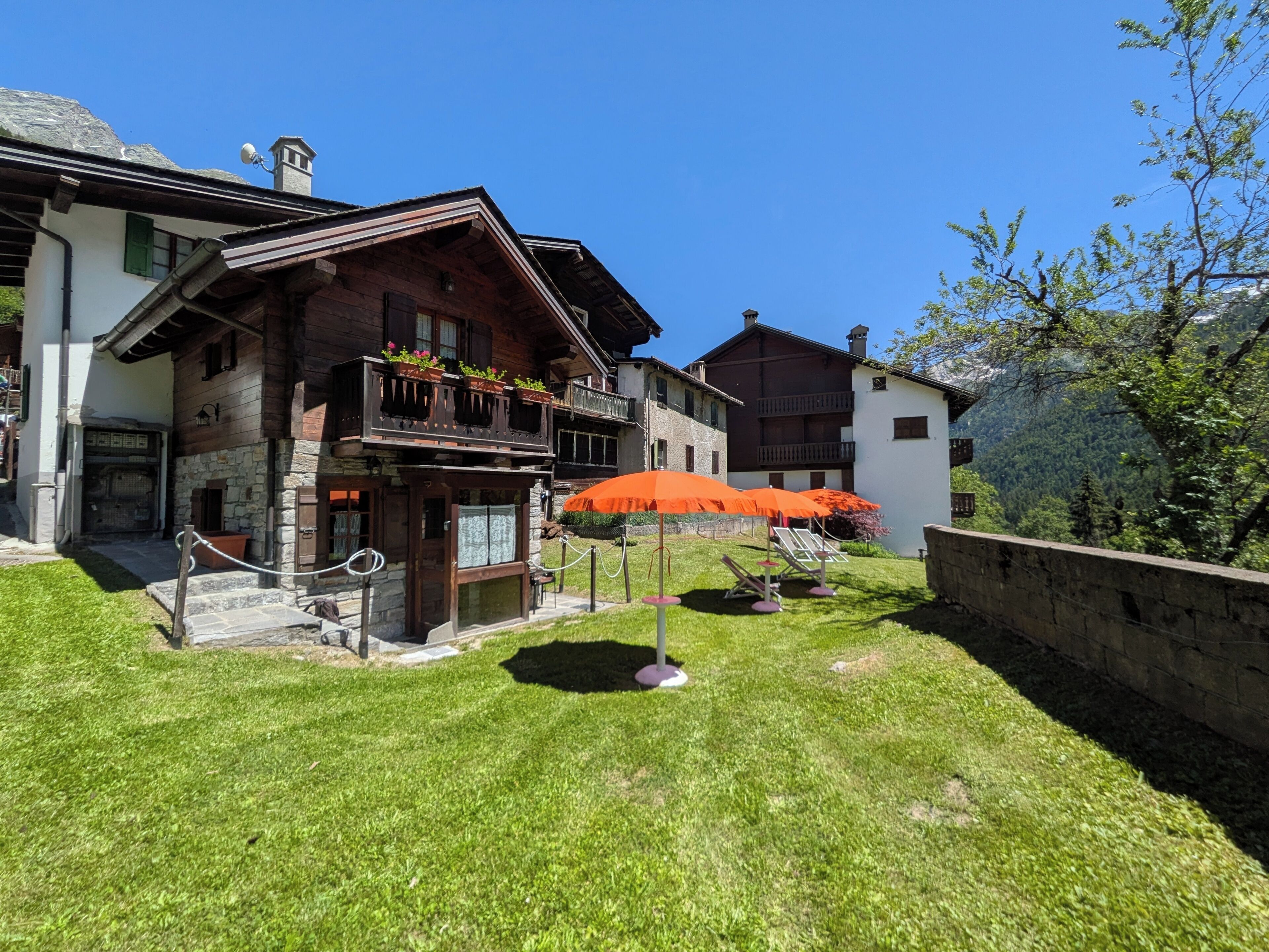 A traditional chalet with a stone facade, wooden balconies, and a well-maintained lawn.