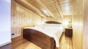Een slaapkamer met houten lambrisering, een enkel bed, nachtkastje en een wandlamp.