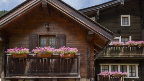 Een houten chalet met een balkon versierd met bloembakken.
