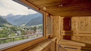 Una sauna de madera con un ventanal grande que ofrece vistas a un paisaje montañoso.