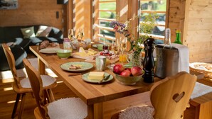 Una mesa de comedor de madera dispuesta con platos, cuencos y cubiertos, rodeada de sillas de madera.