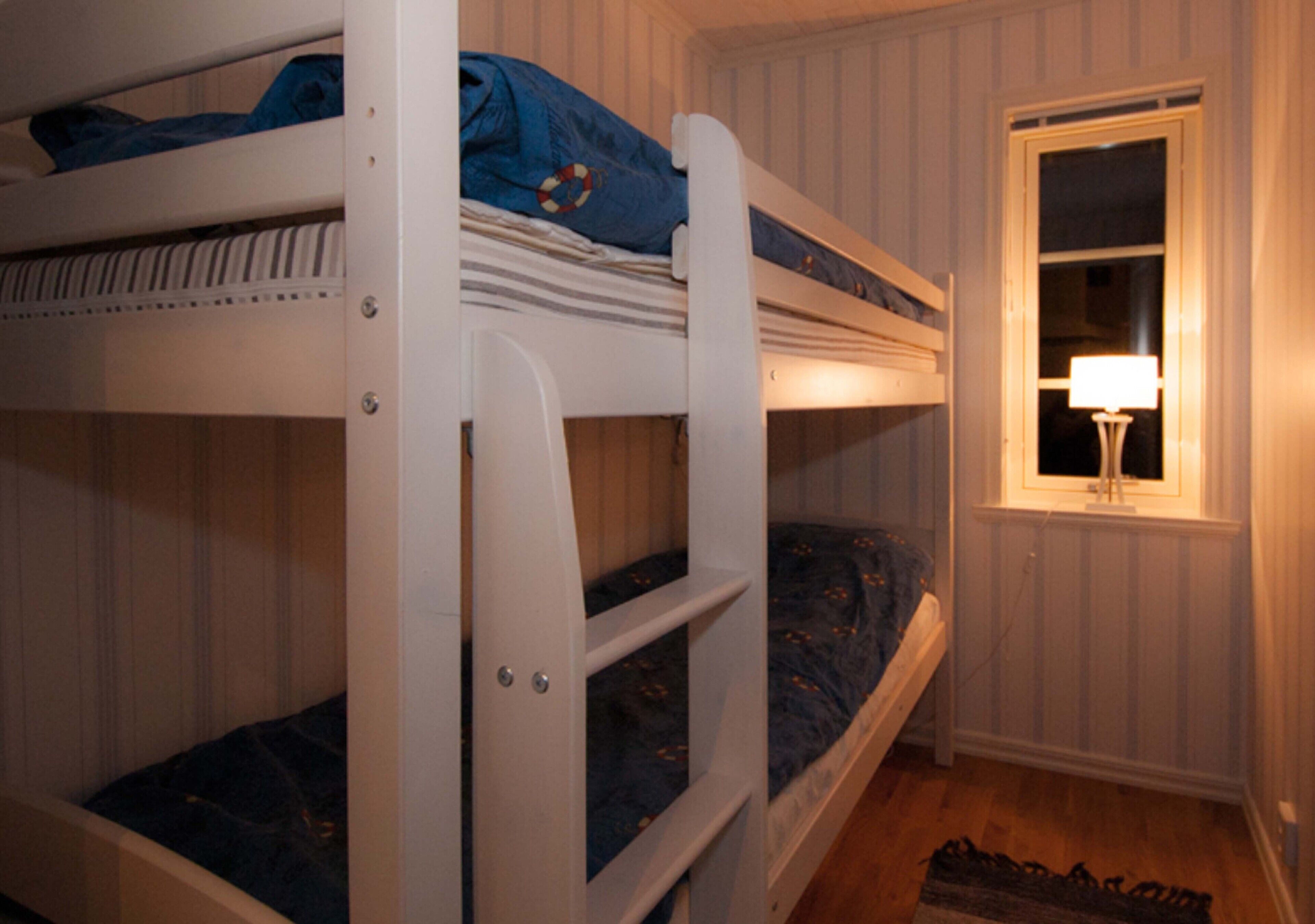 A bunk bed room with a window and a nightstand.