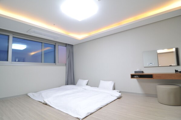 Una habitación de hotel moderna con una cama, una mesita de noche, un espejo y una ventana con cortinas.