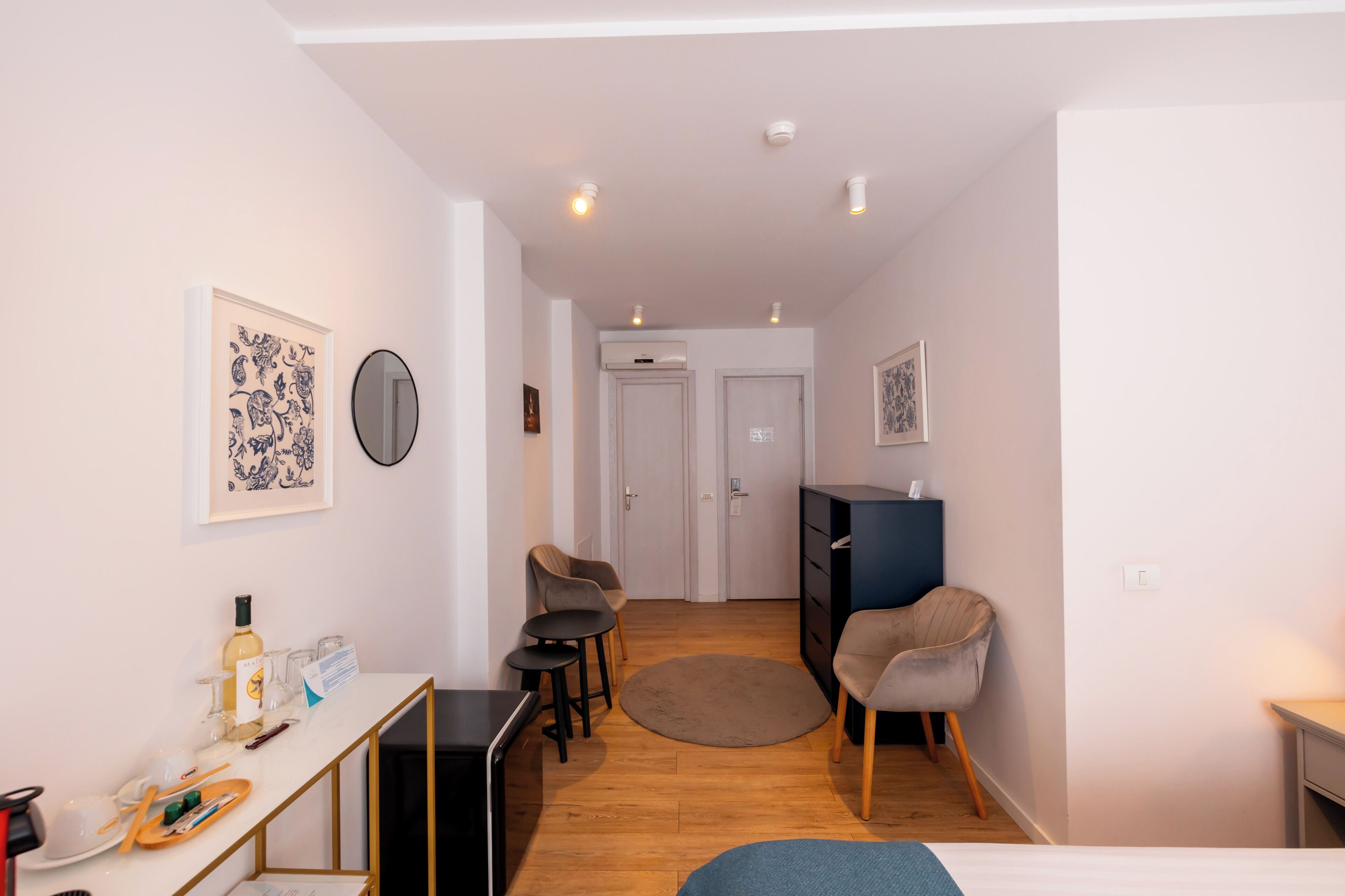 A compact hotel room with a bed, a desk, a chair, a small table, and a wardrobe.