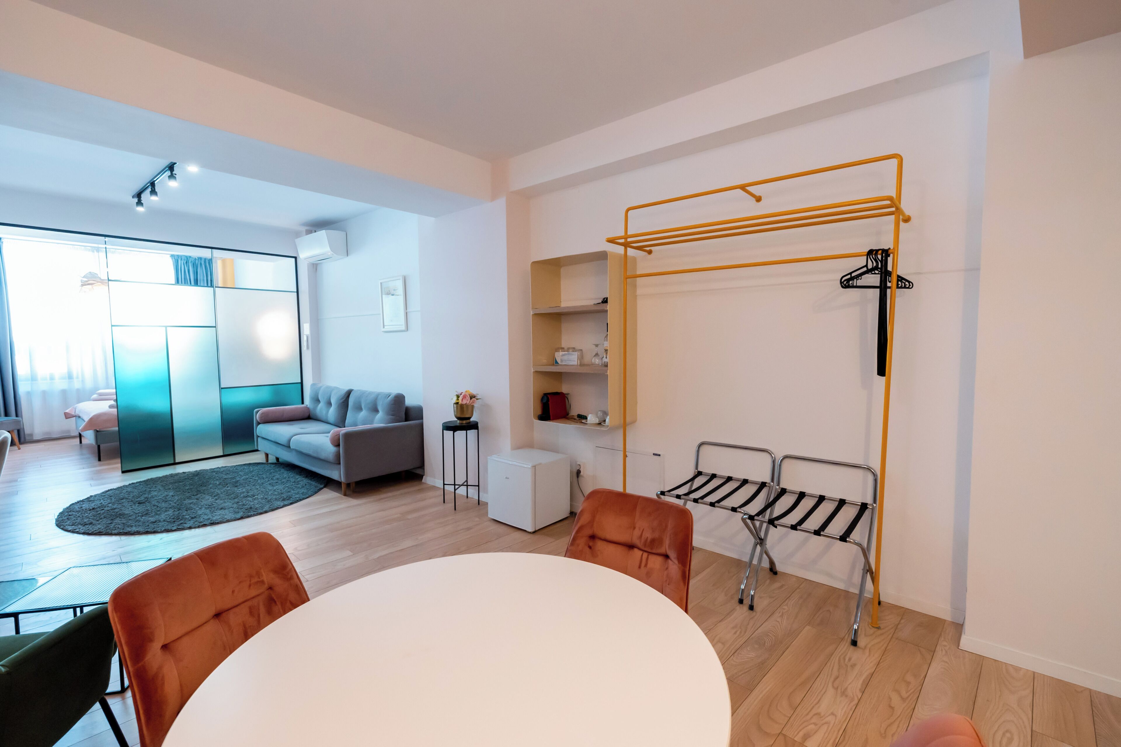 A modern room with a dining table, sofa, and a compact kitchenette.