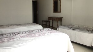 Una habitación con dos camas, una mesita de madera, un espejo y un televisor montado en la pared.