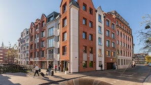 En flervåningsbostadsbyggnad med en blandning av tegel- och modern fasad, utrustad med balkonger och stora fönster.