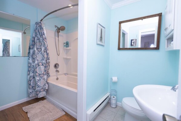 A bathroom with a shower, toilet, and sink.