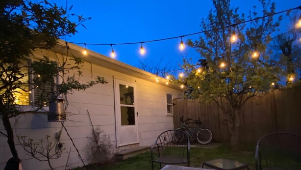 A backyard with a fire pit, a dog, and string lights.