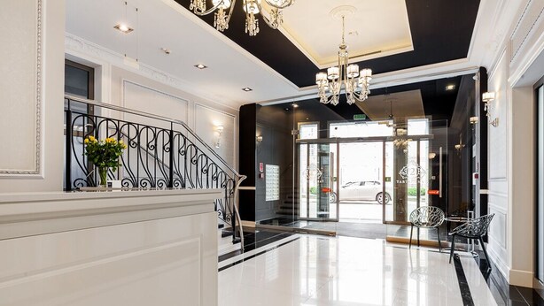 A spacious lobby with a black and white color scheme, a grand staircase, and a chandelier. - Happy Stay Old Town Tartaczna 26 A (Gdansk)