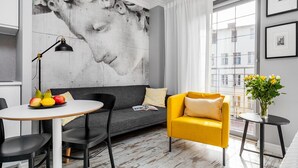 A modern living room with a grey sofa, a yellow armchair, a round table with fruits, a black floor lamp, and a large abstract painting on the wall. - Happy Stay Old Town Tartaczna 26 A (Gdansk)