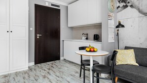 A compact living space with a kitchenette, a dining area with a table and chairs, and a sofa with a cushion. - Happy Stay Old Town Tartaczna 26 A (Gdansk)
