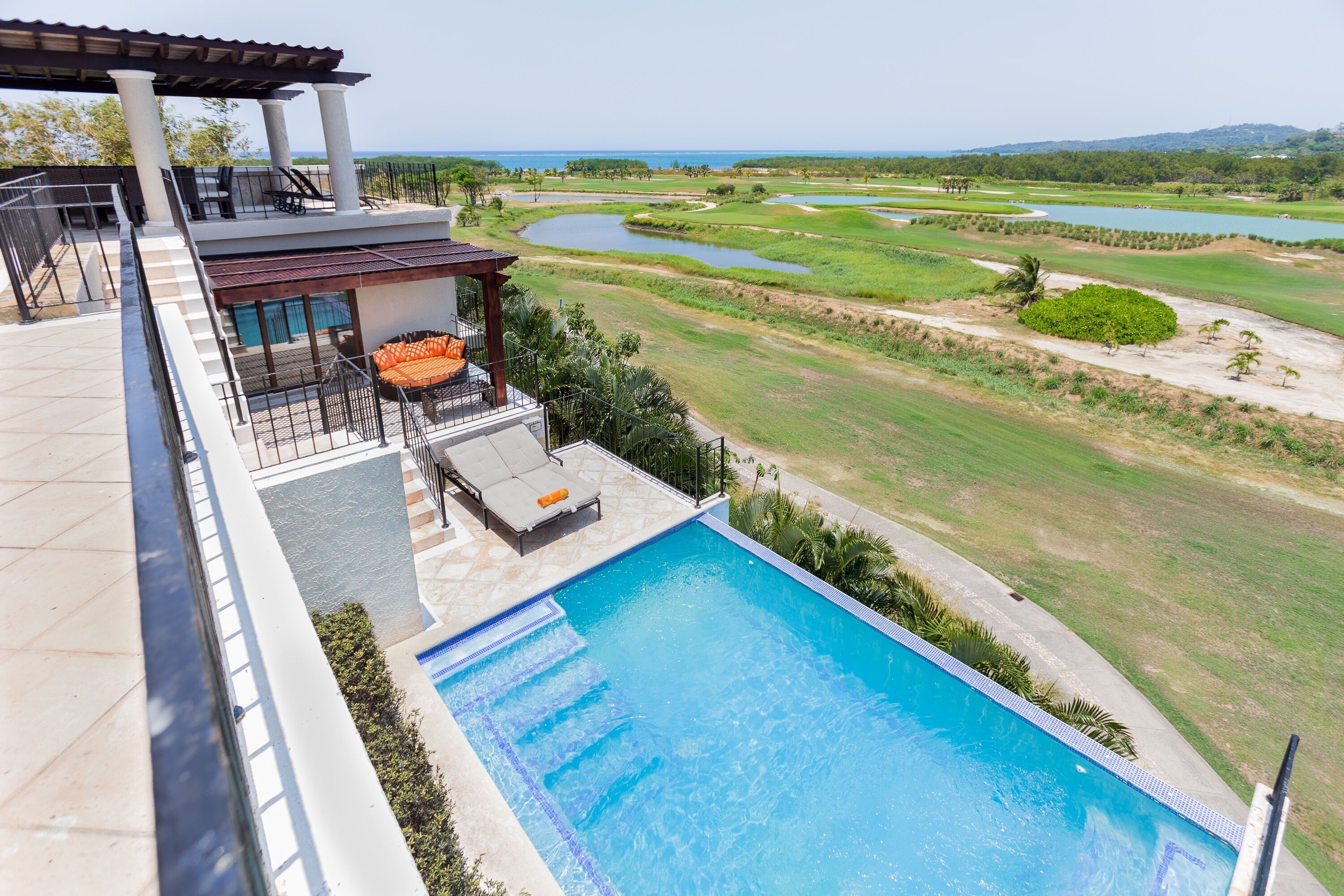 Une piscine avec vue sur un terrain de golf et sur un plan d’eau.