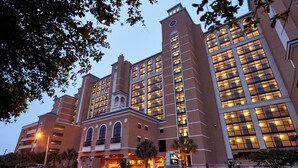 Un hotel grande de varios pisos con una torre de reloj destacada y ventanas arqueadas.