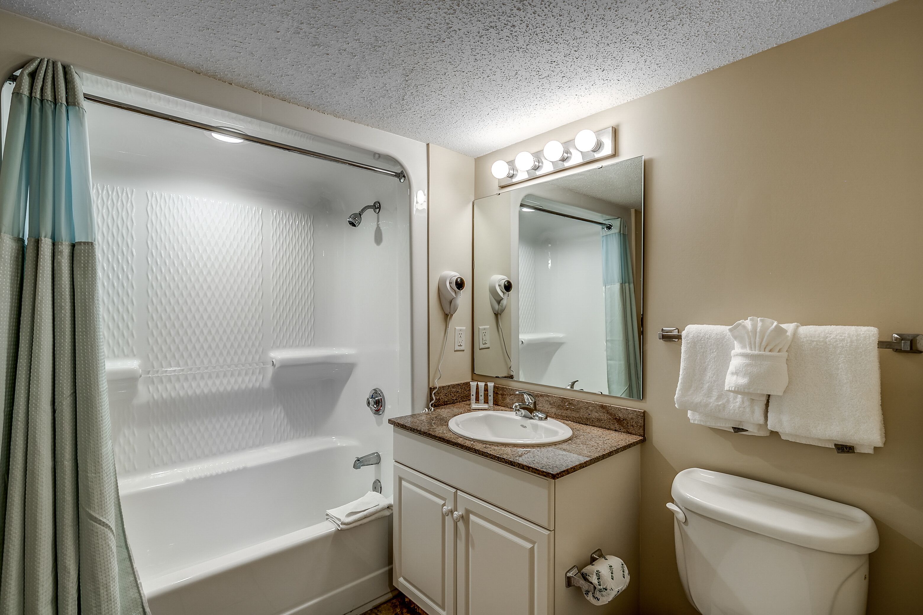 A bathroom with a bathtub, sink, mirror, and toilet.