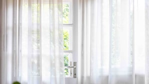 A room with a bed, a window with sheer curtains, and a view of greenery outside. - Delightful apartment from the late 20s, recently renovated. (Merano)