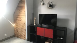 Un salon moderne avec un plafond en pente en bois, un meuble de rangement noir avec des portes rouges et deux cages à oiseaux fixées au mur.