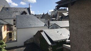 On aperçoit un quartier résidentiel avec de nombreuses maisons, certaines dotées de toits en pente et d’autres de toits plats. Une cheminée est visible sur l’une des maisons, et une croix sur un mât se trouve à l’arrière-plan.