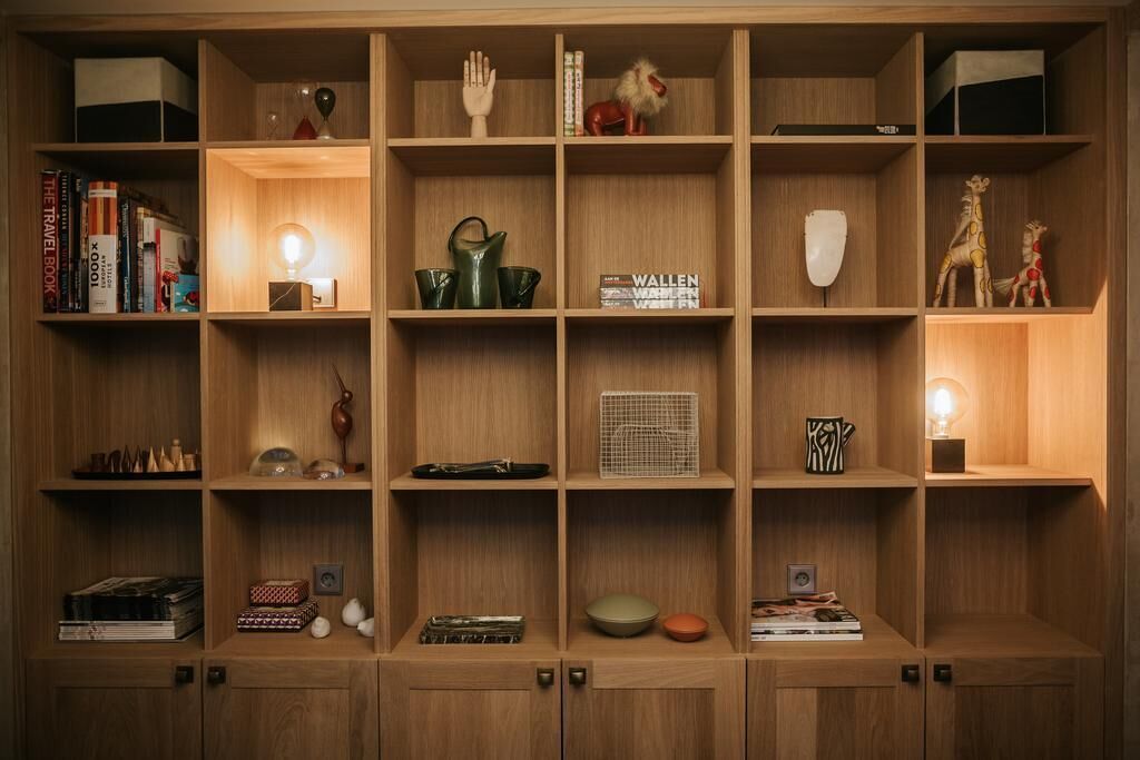 Ein Holzregal mit verschiedenen Gegenständen, darunter Bücher, Dekoration und einer Lampe.