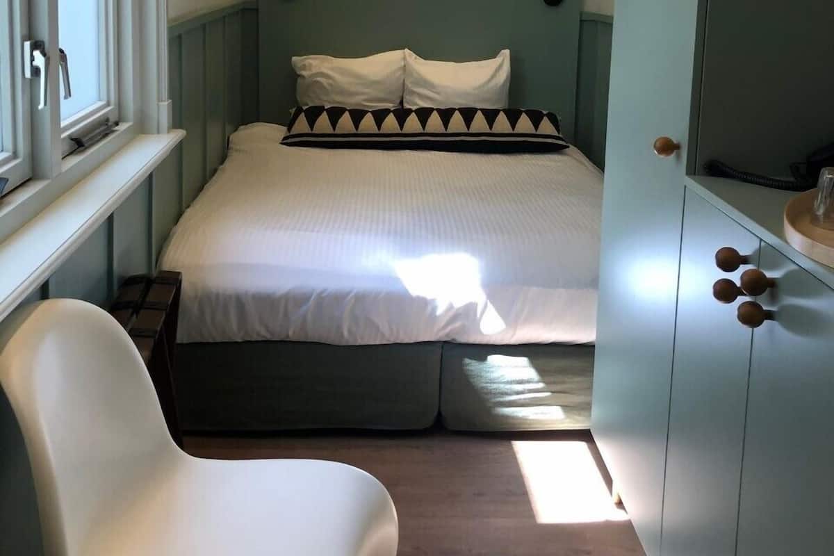 A bedroom with a bed, bedside tables, a chair, and a wardrobe.