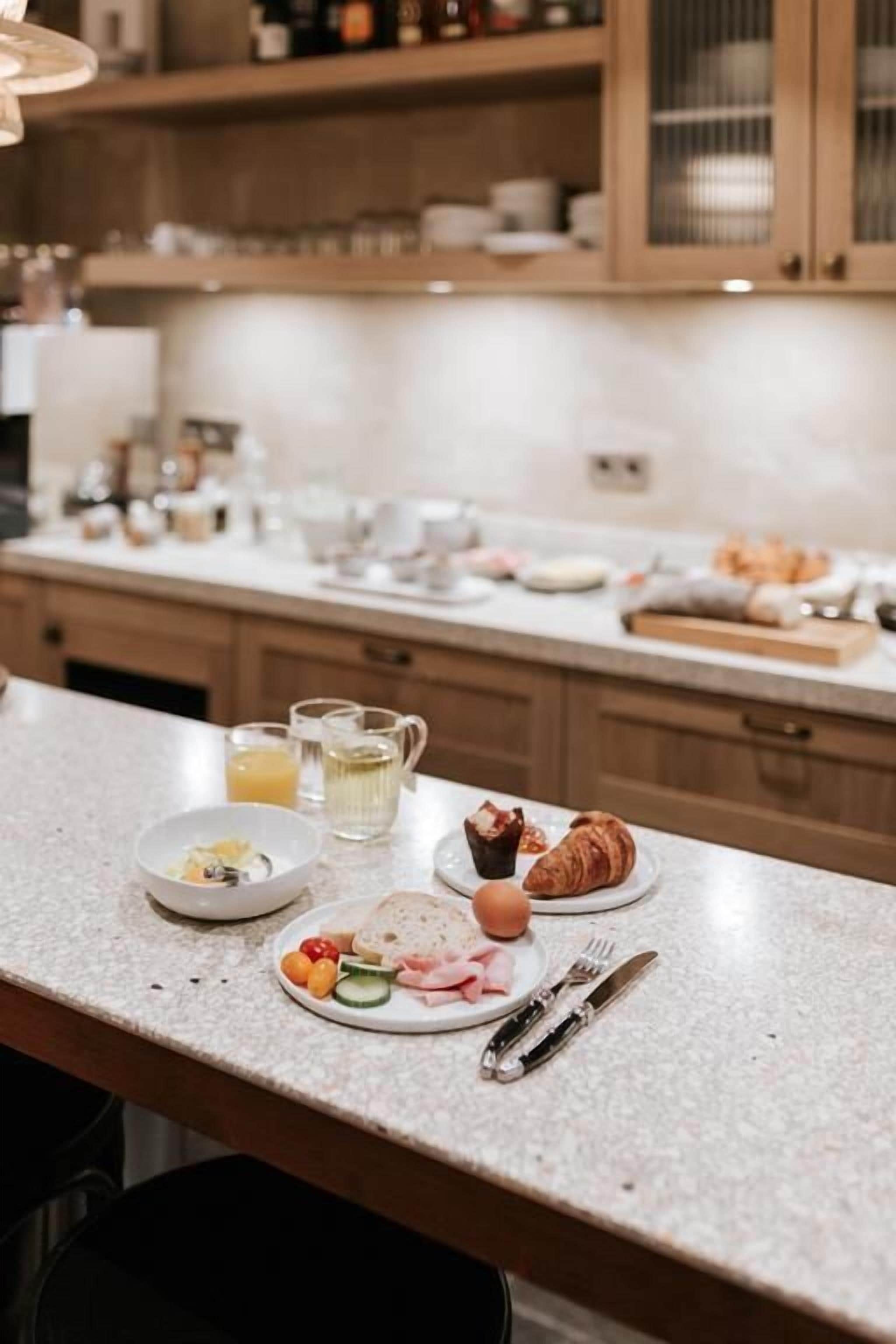 A kitchen counter with breakfast items including eggs, croissants, and a plate of vegetables.