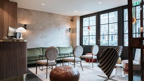Eine moderne Lobby mit einer Rezeption, einer Sitzecke und großen Fenstern mit Blick auf die Stadt.