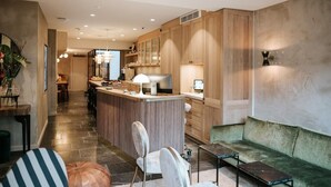 Eine moderne Küche mit Holzsäulen, einer zentralen Kochinsel und einem grünen Sofa.