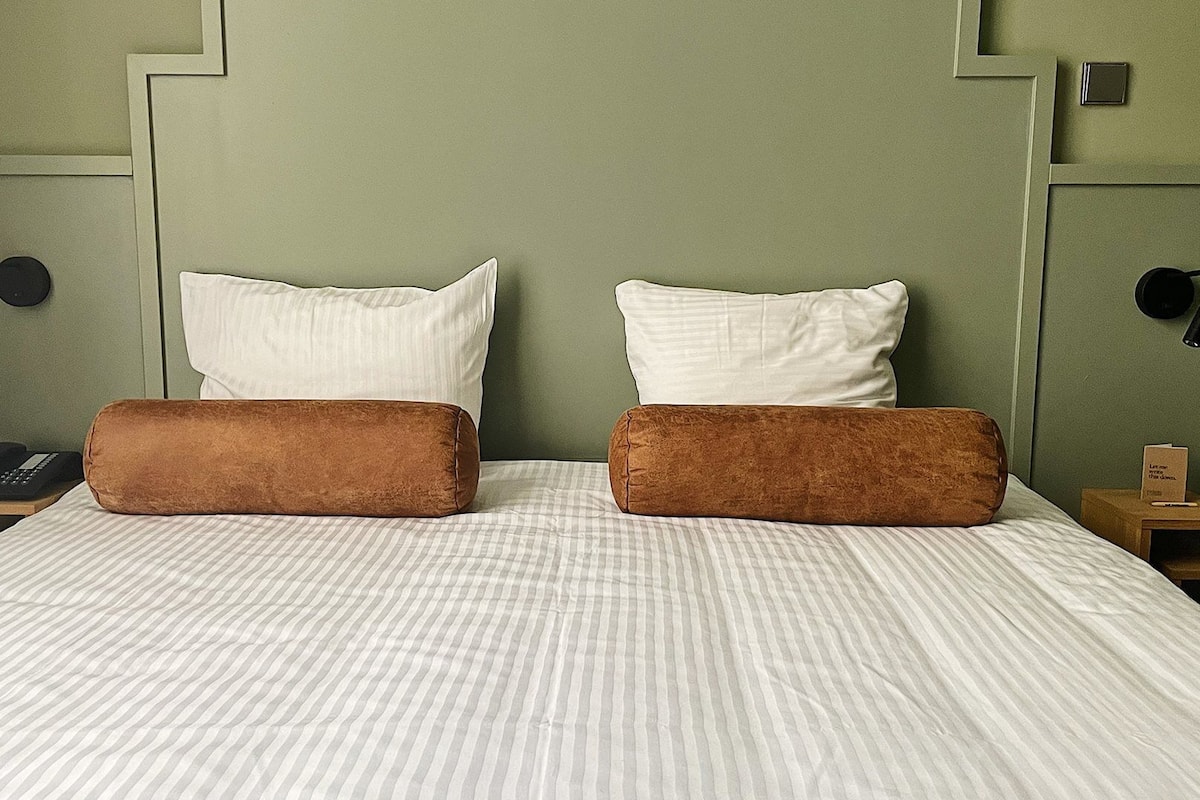 A bed with two pillows, a striped bedspread, and a headboard with a geometric design.