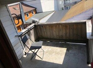 A small outdoor balcony with a folding chair, a security camera, and a wooden fence. -  Keybutler City Apartment Henrik Wergelands (Kristiansand)