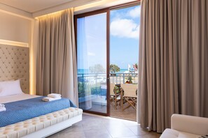 A hotel room with a bed, a sofa, a balcony with a table and chairs, and curtains. - Kahlua Bay Apartments (Hersonissos)
