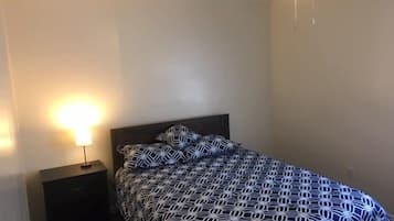 Ein Schlafzimmer mit einem Bett, einem Nachttisch, einer Lampe und einem Deckenventilator.