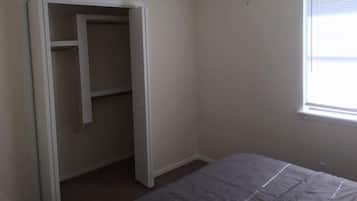 Ein Schlafzimmer mit Bett, Schrank, Deckenventilator und Fenster.
