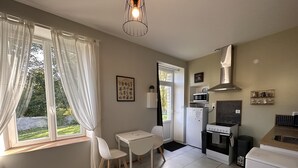 A compact kitchen with a dining area, a refrigerator, a microwave, a stove, and a sink. - Côté Jardin" self-catering cottage, Contrexéville spa resort (Contrexéville)