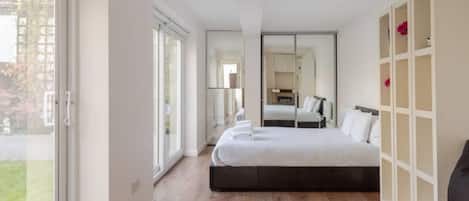A modern hotel room with a large bed, a glass coffee table, and a view of the outdoors.