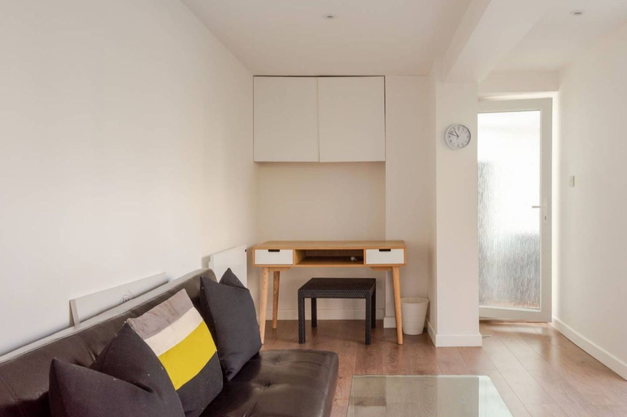 A modern living room with a sofa, a desk, and a small table.