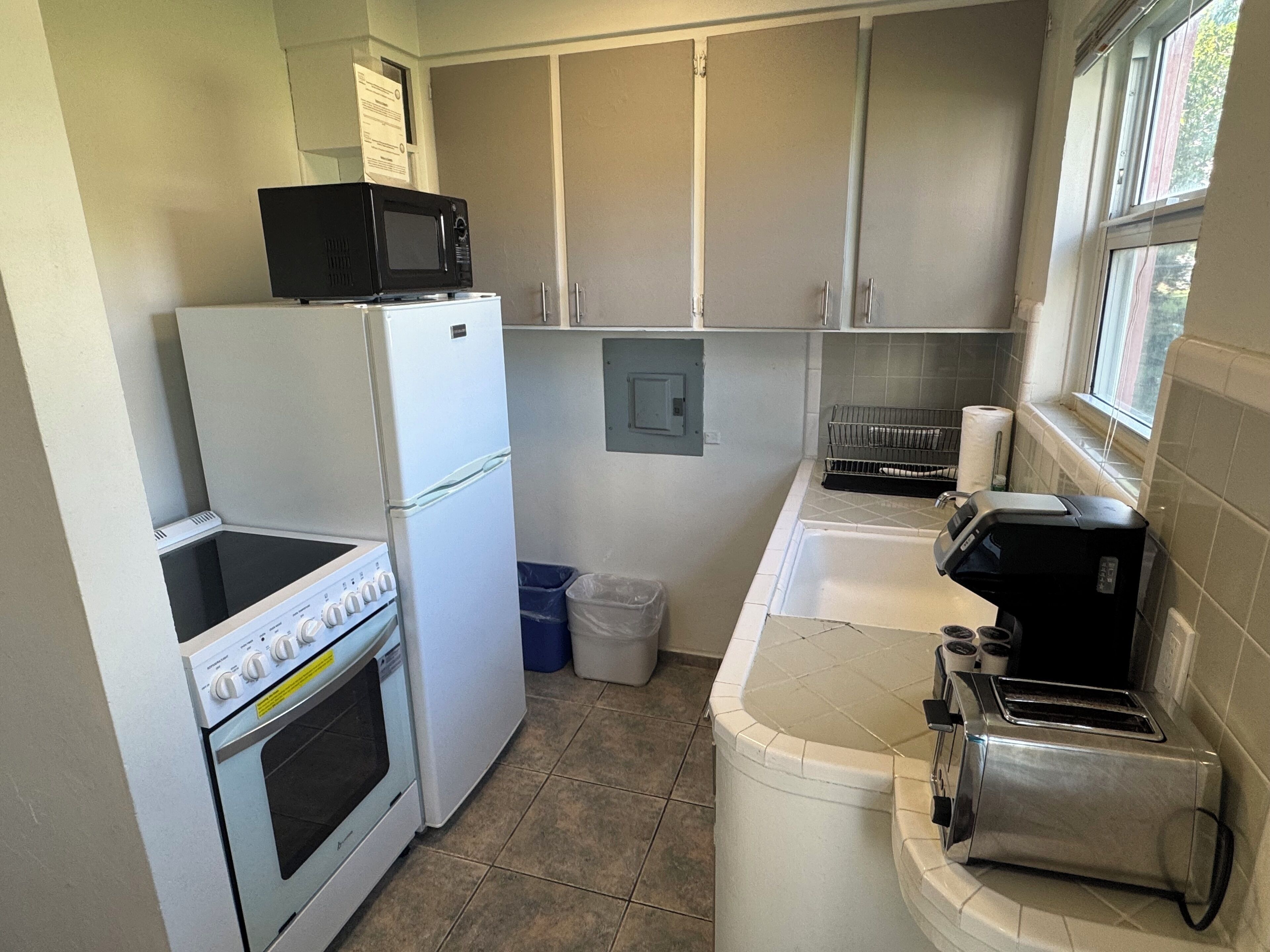 A compact kitchen with a stove, microwave, refrigerator, and toaster.