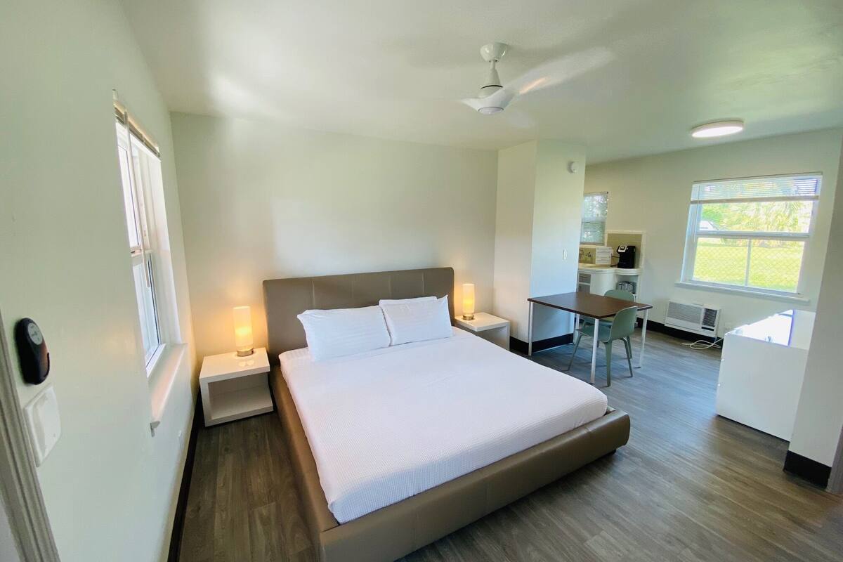 A hotel room with a bed, bedside tables, a desk, and a chair.