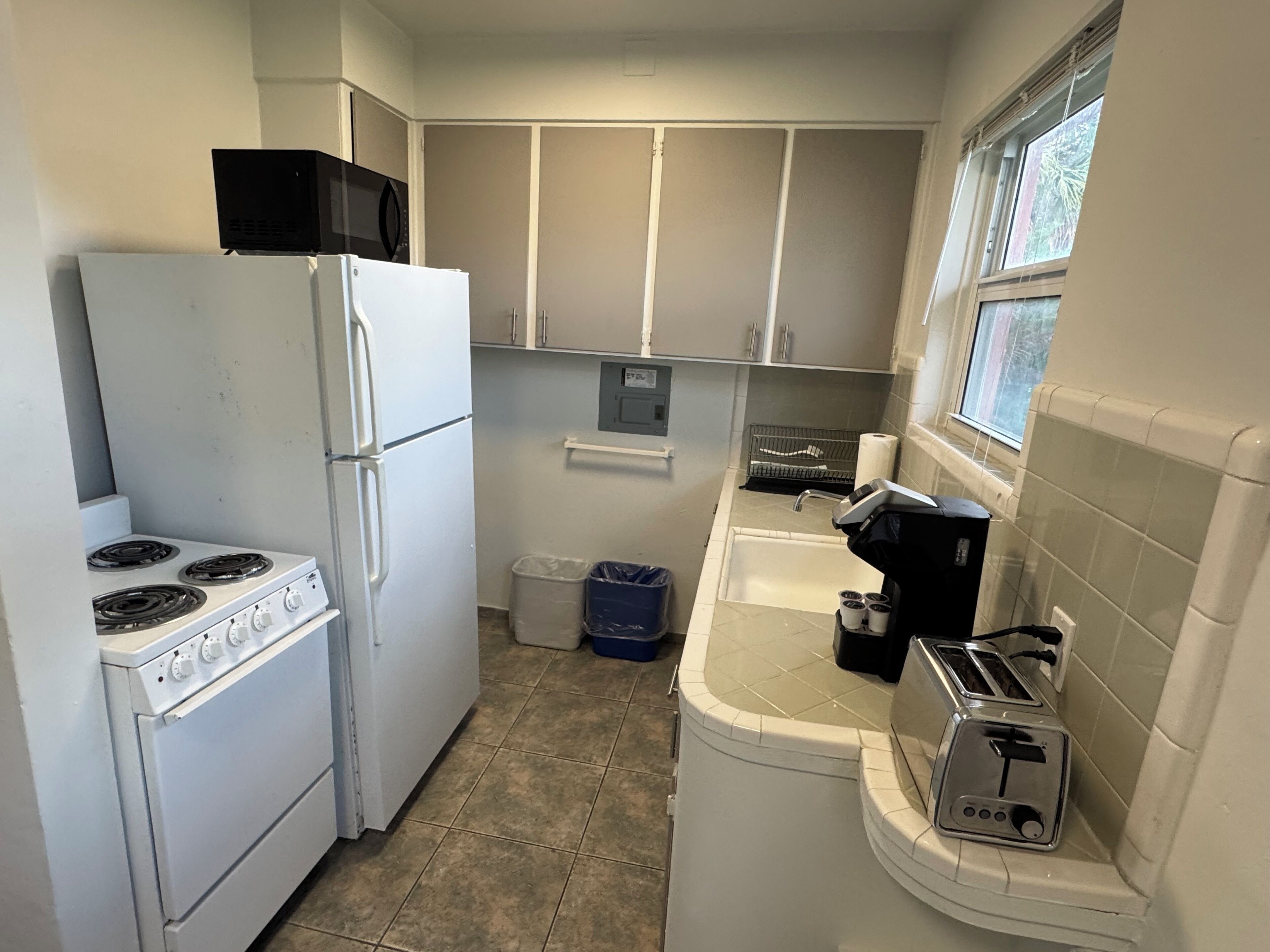 Cocina compacta con estufa, refrigerador y tostadora.