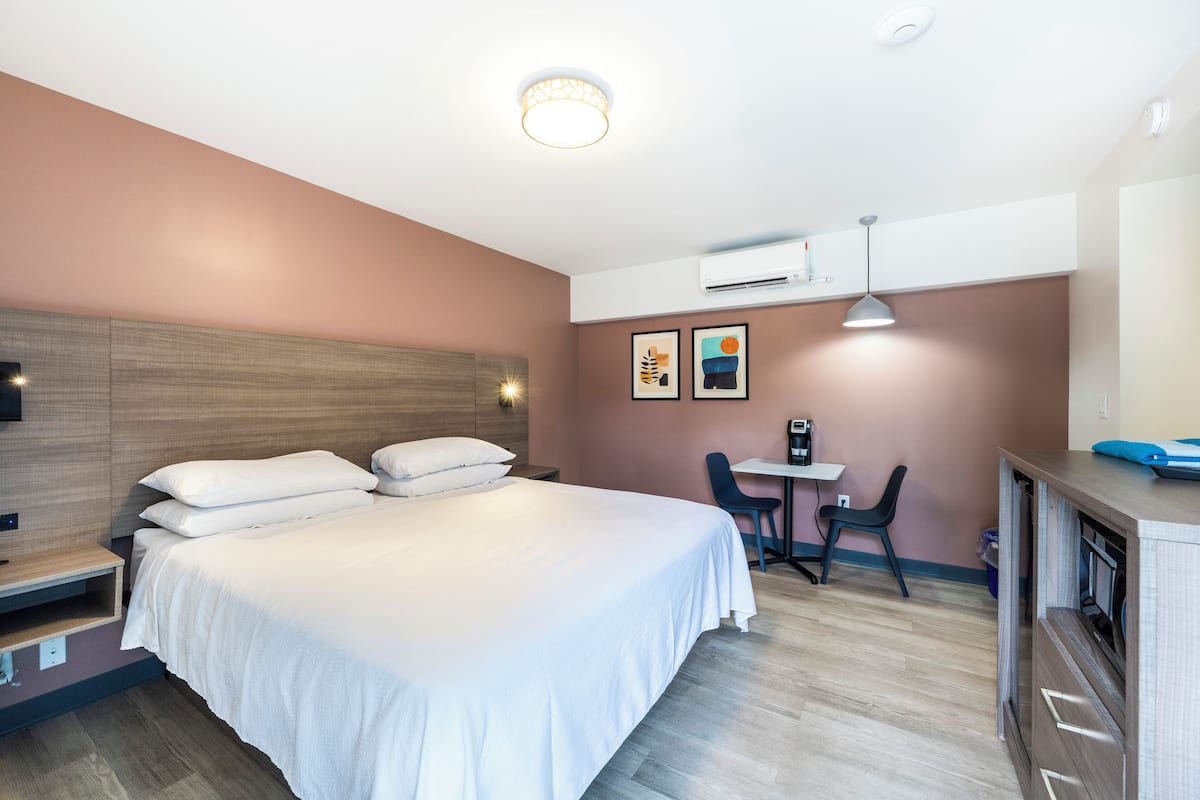 A hotel room with a large bed, a desk, and a chair.