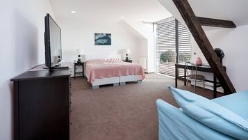Ein Schlafzimmer mit Bett, Nachttischen, einem Fernseher und einem Fenster mit Jalousien.