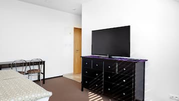 Une chambre d’hôtel comprenant un lit, un bureau avec une chaise, une commode et un téléviseur à écran plat fixé au mur.