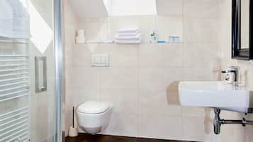 A modern bathroom with a glass shower enclosure, a white toilet, and a sink with a mirror.