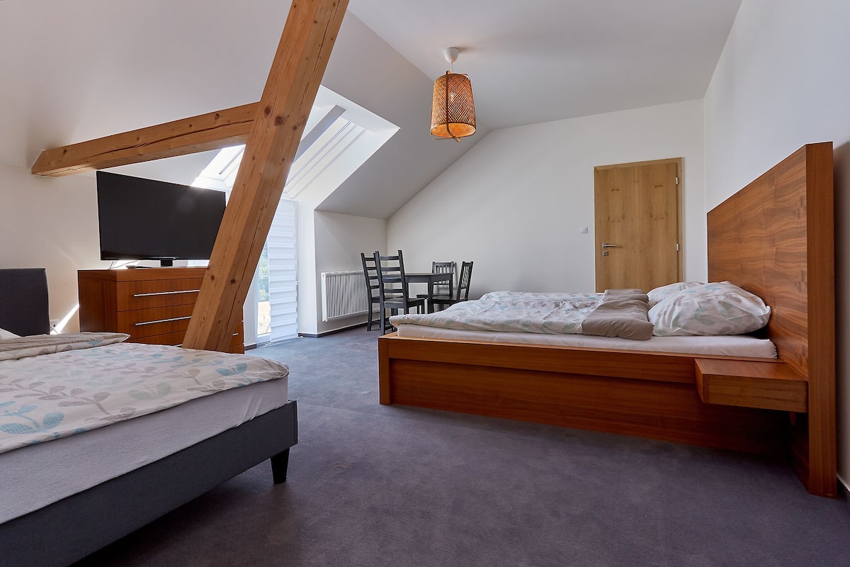 Un dormitorio con techo inclinado, una cama de madera, un televisor y una mesa de comedor.