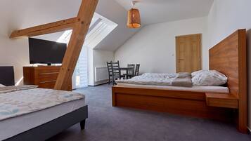 Ein Schlafzimmer mit schrägen Wänden, einem hölzernen Bett, einem Fernseher und einem Esstisch.